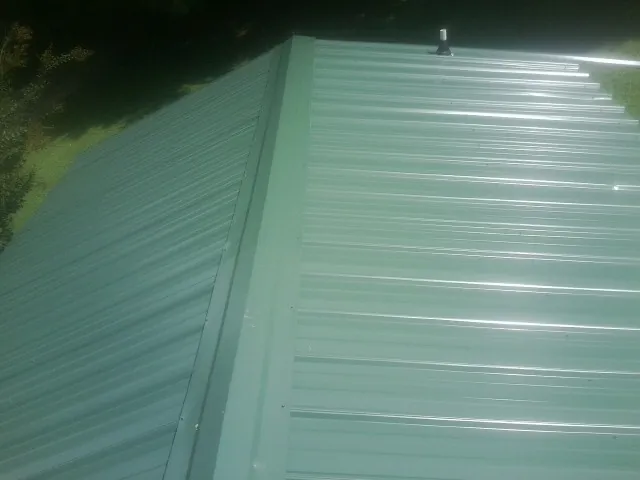 New green metal panels meeting at the ridge of a roof — Flat Roof Repair work by our crew in Ocean City